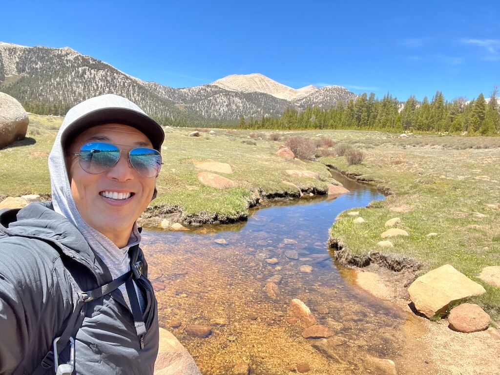 Jeff standing in front of a scenic view at Horseshoe Meadows, with clear blue skies and the Sierra mountains in the background. A creek flows nearby.