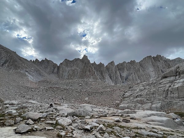Trail Camp at 12,000 feet on the Mount Whitney Main Trail, surrounded by jagged mountain ridges and a cloudy sky.