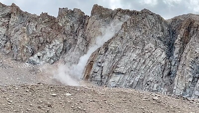 Rock fall near Trail Camp on the Mount Whitney Trail, with dust rising from the impact.